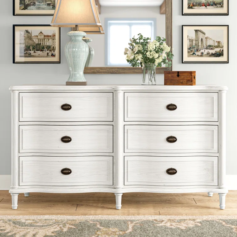 Elegant white six-drawer dresser with oval brass handles styled in traditional living room with table lamp and floral arrangement