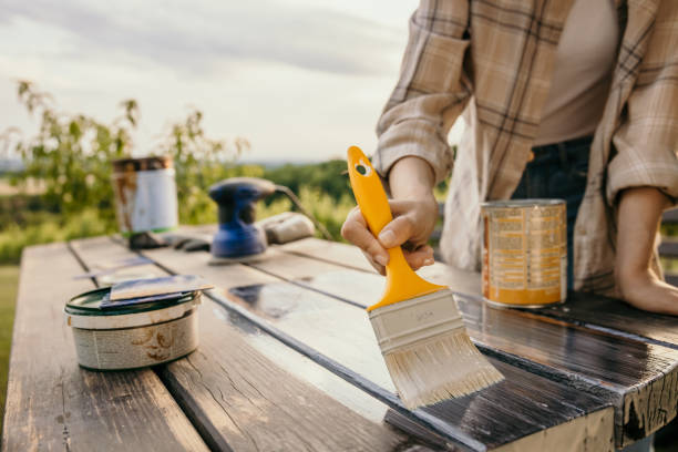 Pouring white paint into roller tray for painting wooden furniture, preparing tools for furniture painting project