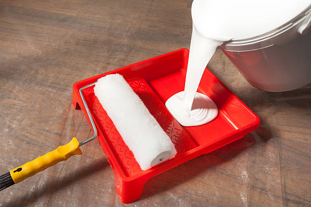 DIY enthusiast using yellow paintbrush for painting on furniture outdoors, applying paint to wooden furniture project